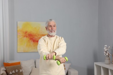 Photo of Elderly man exercising with dumbbells at home