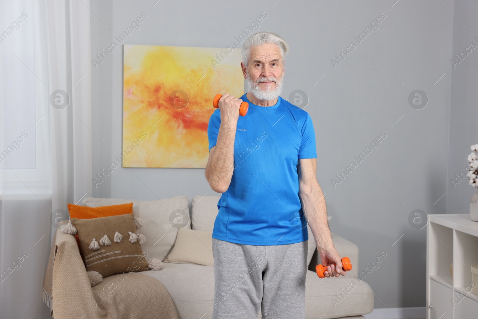 Photo of Elderly man exercising with dumbbells at home