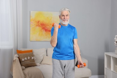 Photo of Elderly man exercising with dumbbells at home