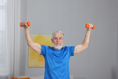 Photo of Elderly man exercising with dumbbells at home