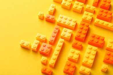 Photo of Constructor toy. Many building blocks on yellow background, above view