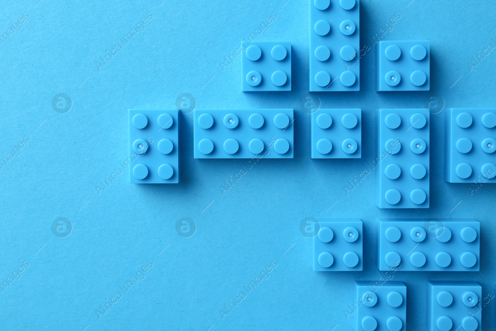 Photo of Constructor toy. Many building blocks on light blue background, flat lay