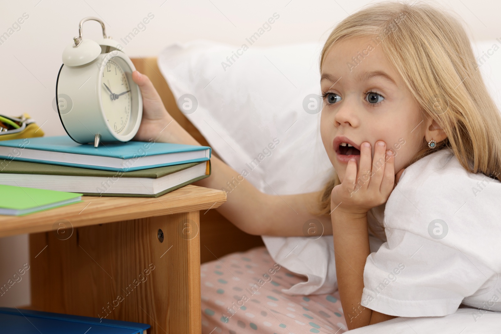 Photo of Overslept girl with alarm clock in bed at home