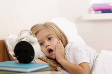 Photo of Overslept girl with alarm clock in bed at home