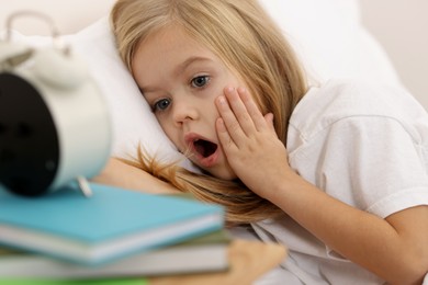 Photo of Overslept girl with alarm clock in bed at home