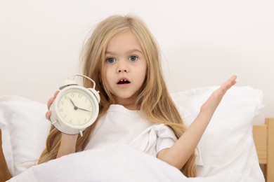 Photo of Overslept girl with alarm clock in bed at home