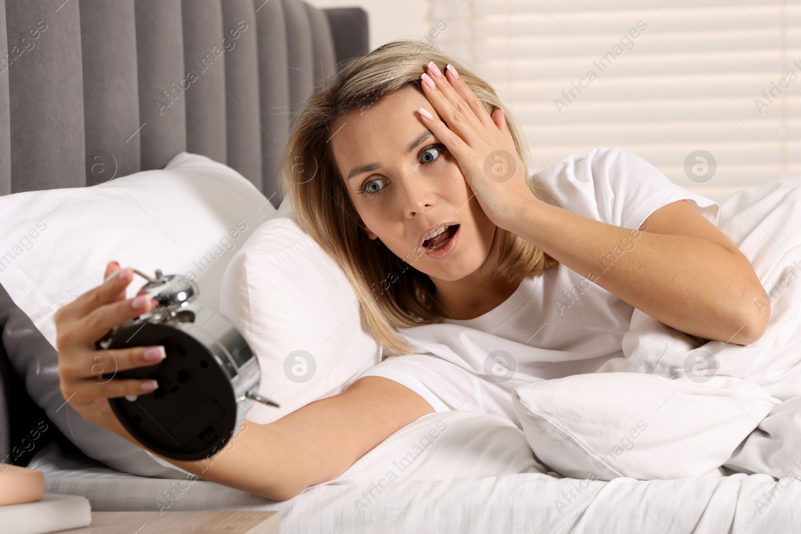 Photo of Overslept woman with alarm clock in bed at home