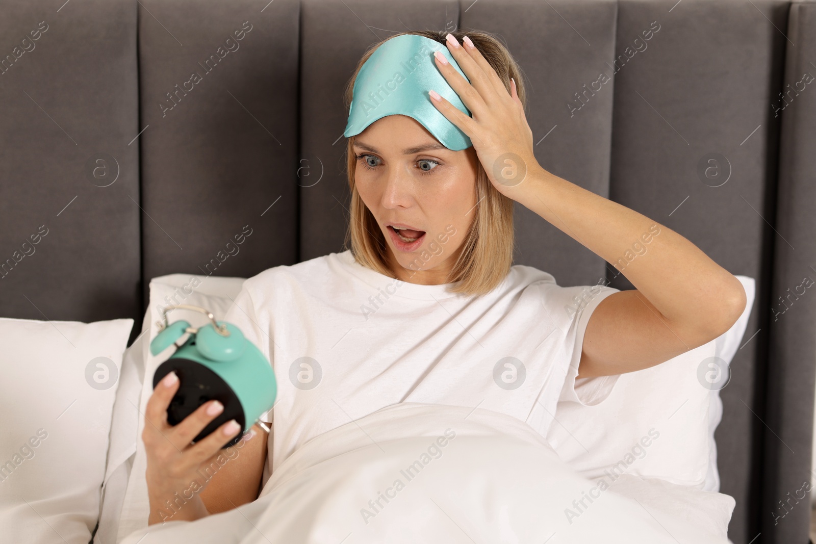 Photo of Overslept woman with alarm clock in bed at home