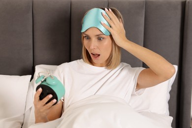 Photo of Overslept woman with alarm clock in bed at home