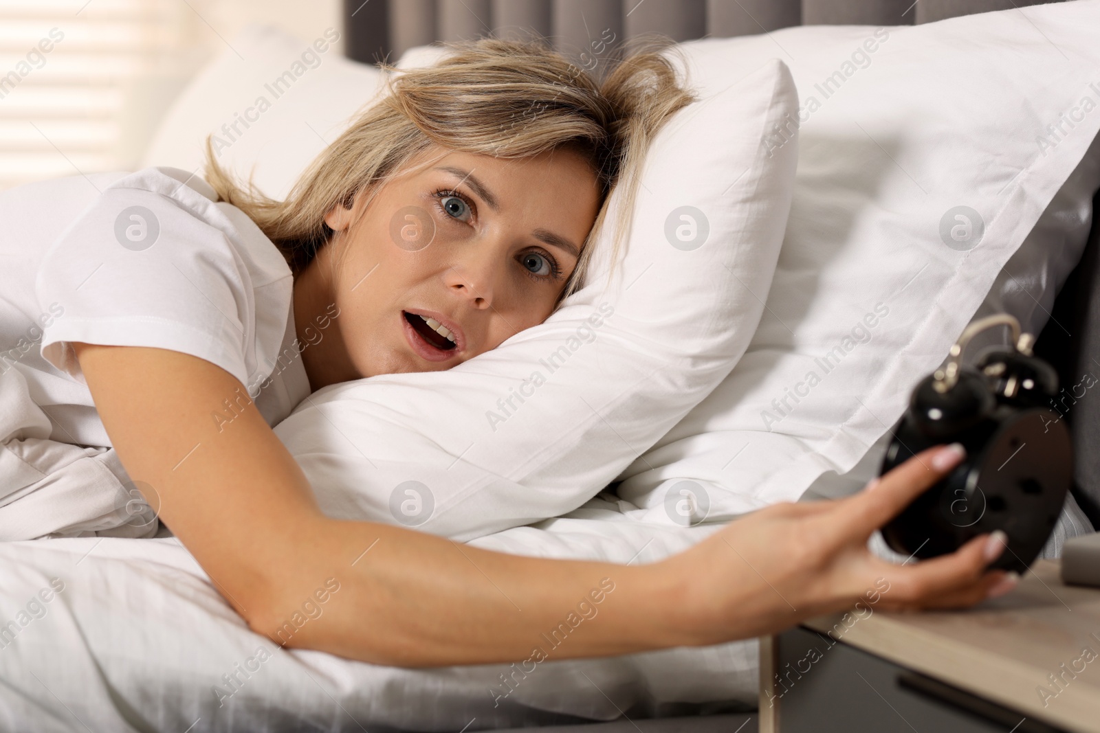 Photo of Overslept woman with alarm clock in bed at home