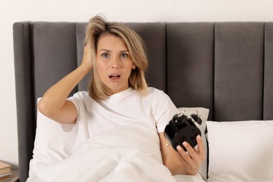 Photo of Overslept woman with alarm clock in bed at home