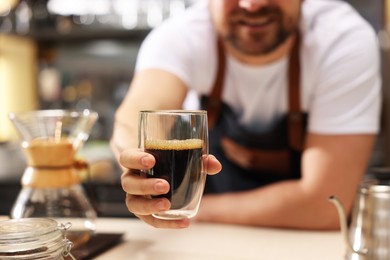 Photo of Barista suggesting cup of aromatic filter coffee in cafe, closeup. Selective focus