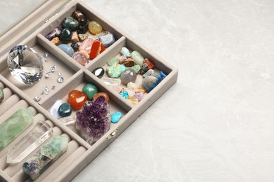 Photo of Box with beautiful gemstones on light table, closeup. Space for text