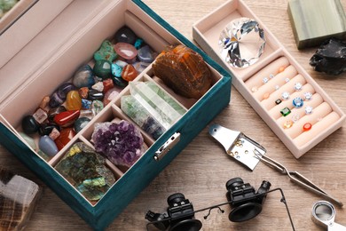 Photo of Box with beautiful gemstones and jeweler's tools on wooden table, closeup