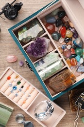 Photo of Box with beautiful gemstones and jeweler's tools on wooden table, flat lay