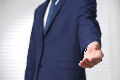 Photo of Man offering helping hand on light background, closeup