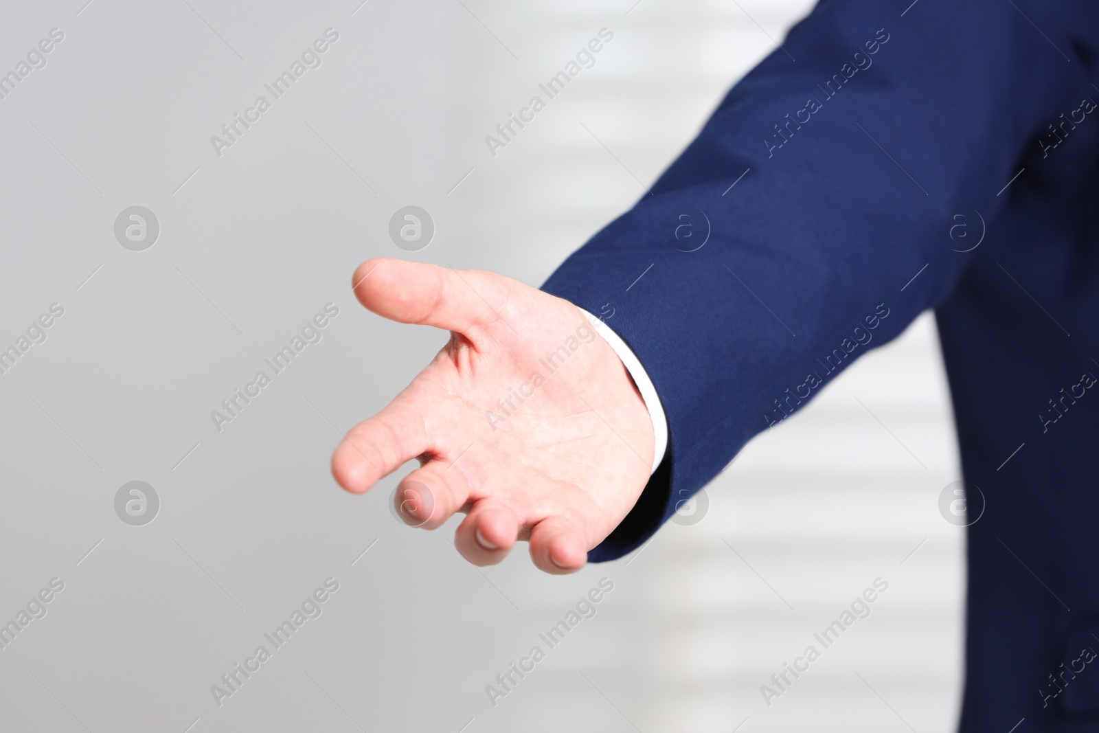 Photo of Man offering helping hand on light background, closeup