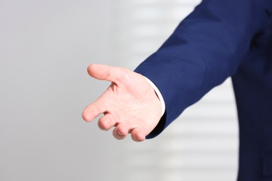 Photo of Man offering helping hand on light background, closeup