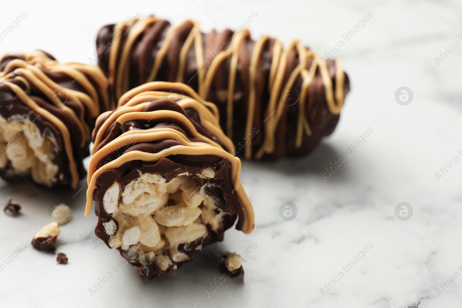 Photo of Delicious chocolate puffed rice bars on white marble table, closeup