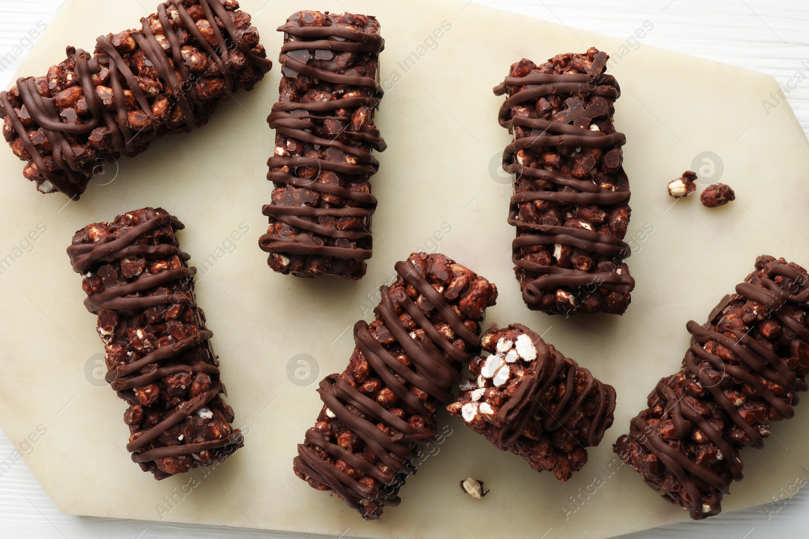 Photo of Delicious chocolate puffed rice bars on white wooden table, top view