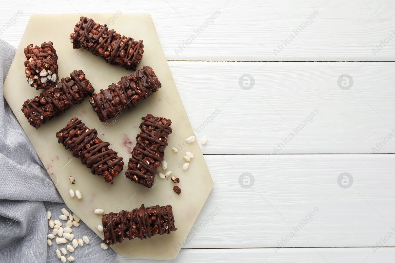 Photo of Delicious chocolate puffed rice bars on white wooden table, top view. Space for text