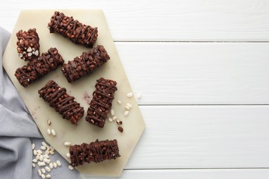 Photo of Delicious chocolate puffed rice bars on white wooden table, top view. Space for text