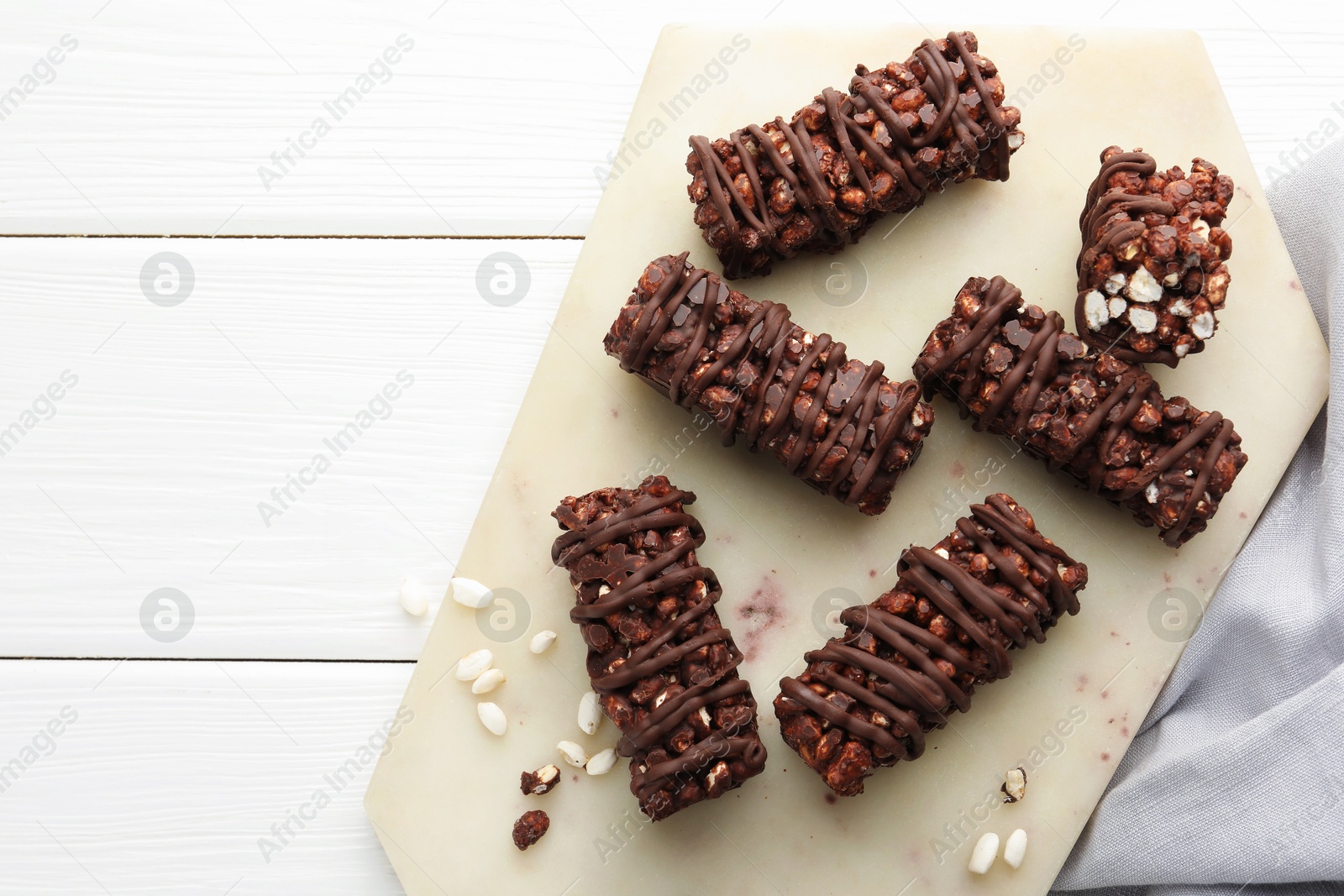 Photo of Delicious chocolate puffed rice bars on white wooden table, top view. Space for text