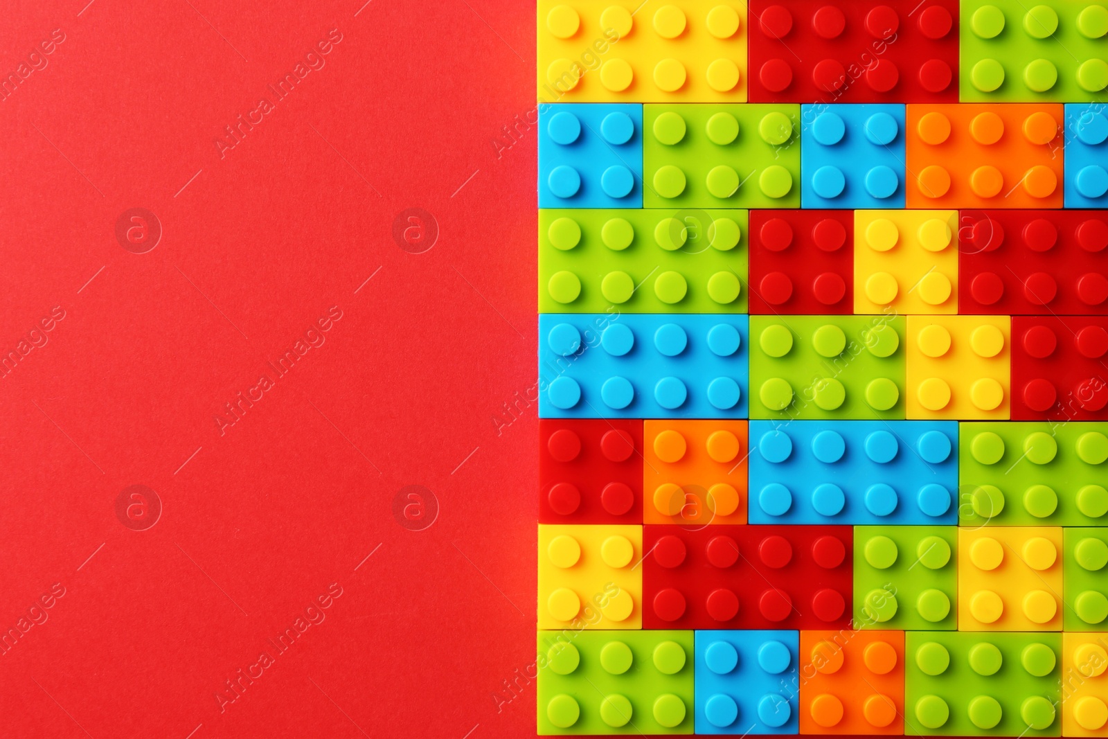 Photo of Construction toy. Colorful building bricks on red background, top view with space for text