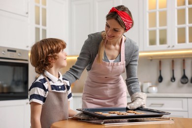 Photo of Mother and her son with homemade cookies at wooden table in kitchen