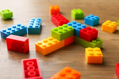 Photo of Construction toy. Colorful building bricks on wooden table, closeup