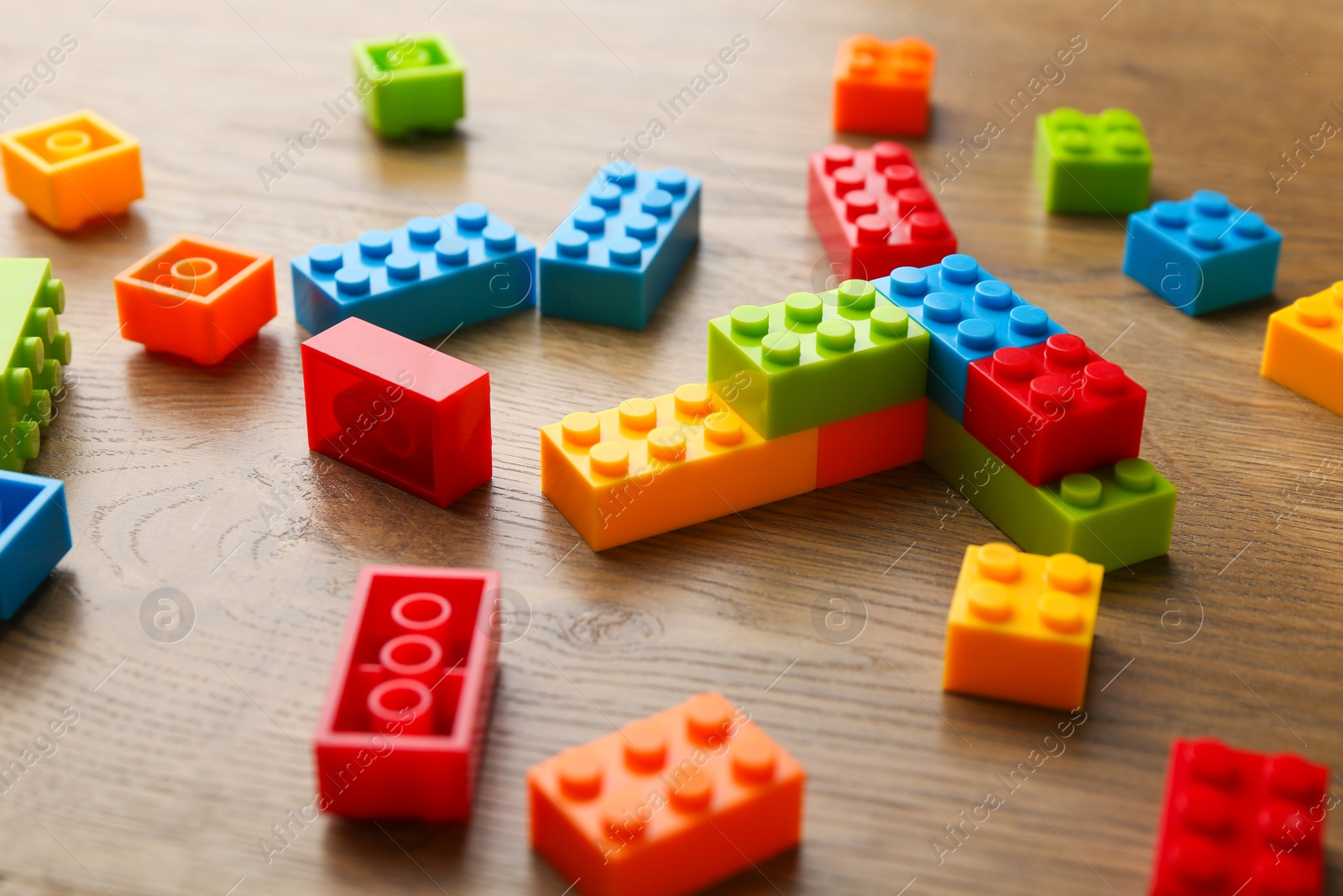 Photo of Construction toy. Colorful building bricks on wooden table, closeup