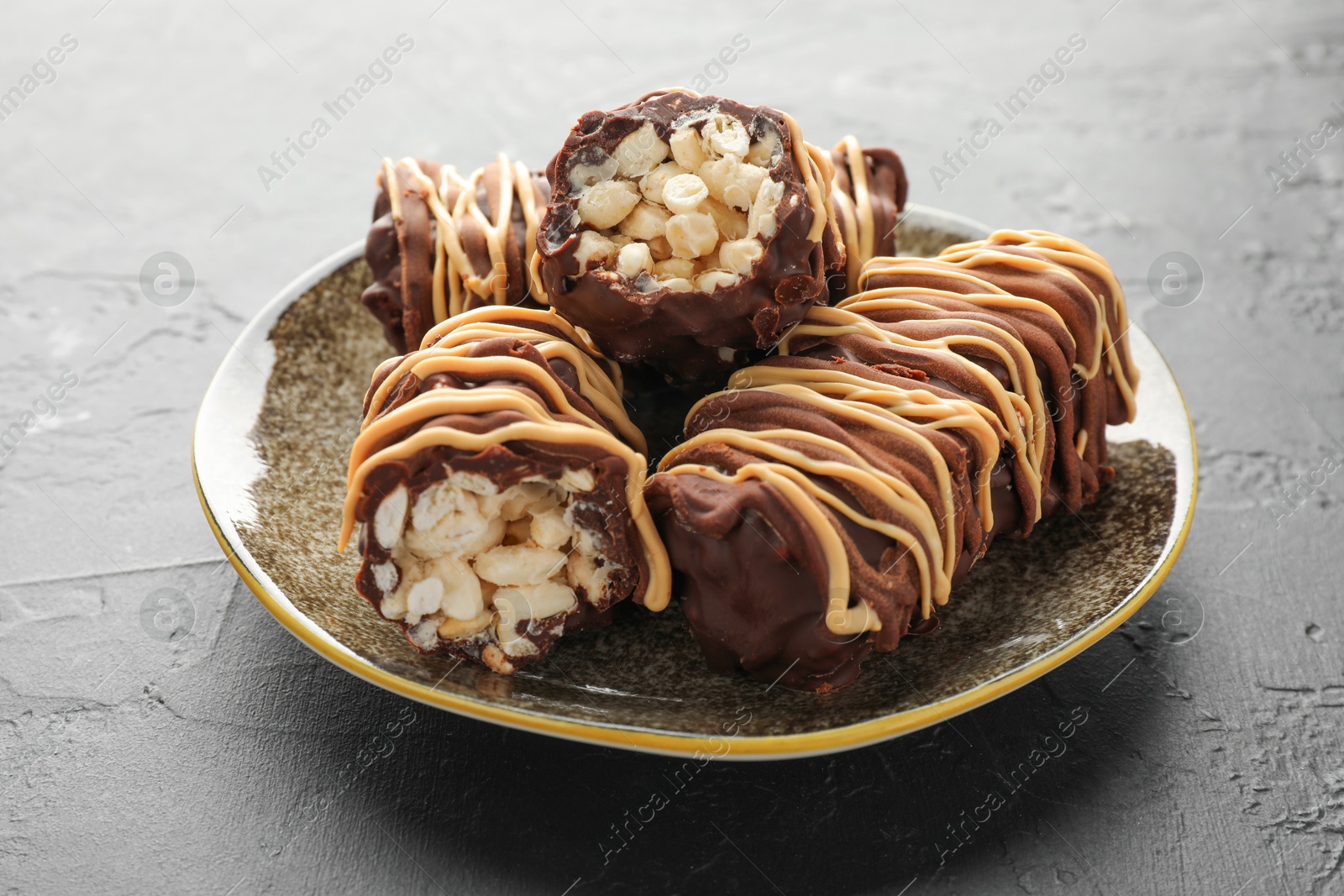 Photo of Delicious chocolate puffed rice bars on gray textured table, closeup