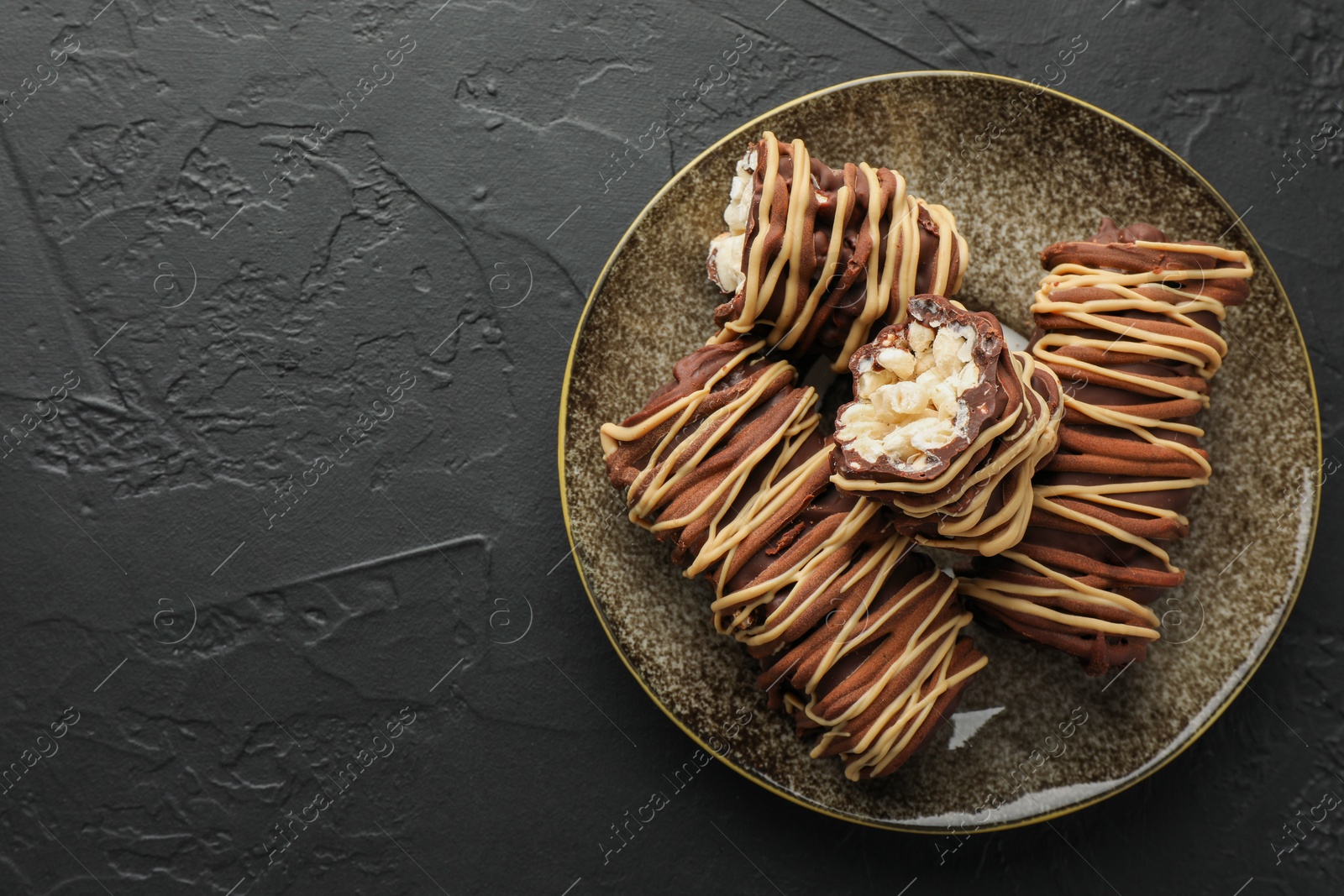 Photo of Delicious chocolate puffed rice bars on dark gray textured table, top view. Space for text