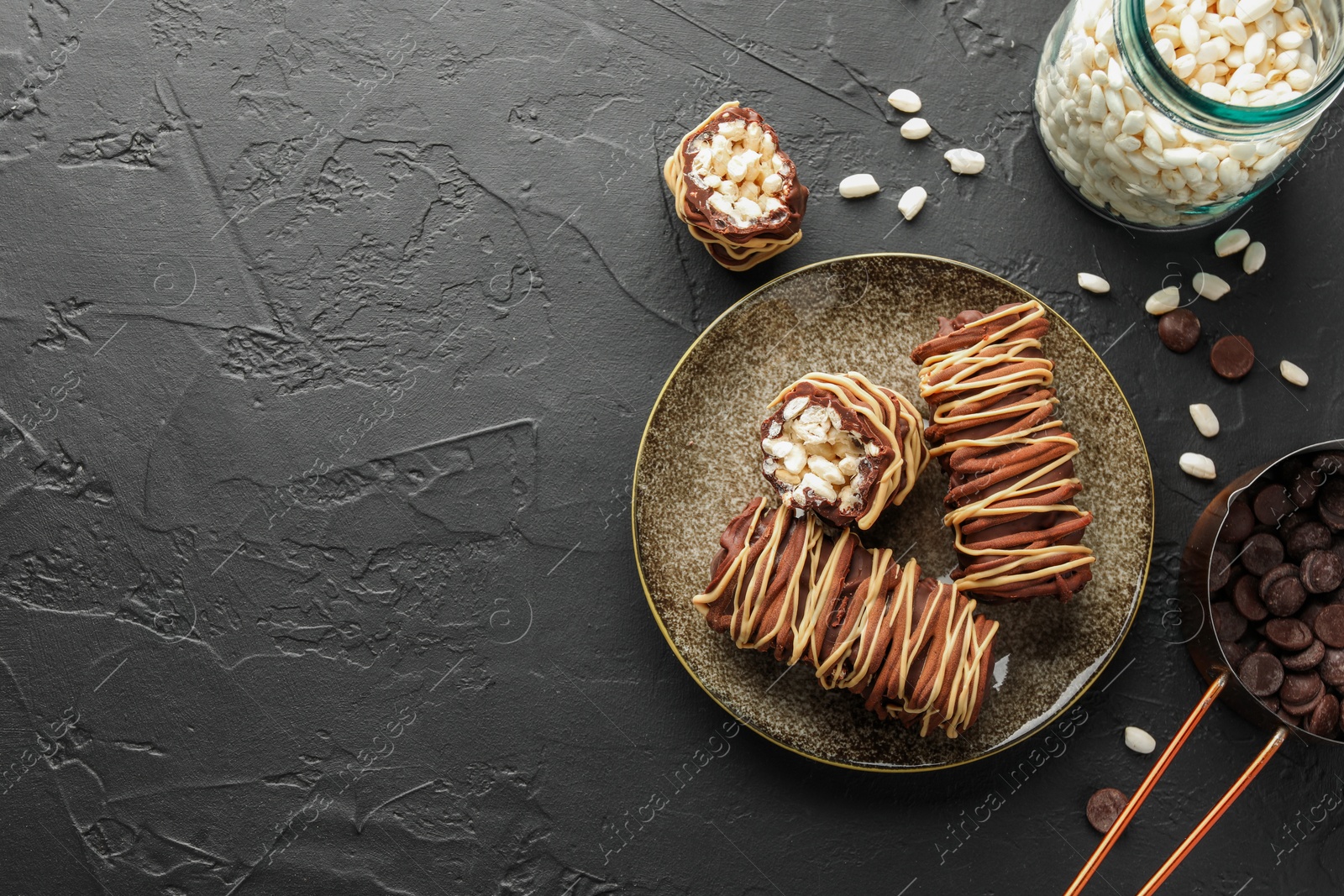 Photo of Delicious chocolate puffed rice bars and ingredients on dark gray textured table, flat lay. Space for text