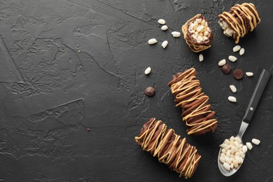 Photo of Delicious chocolate puffed rice bars and spoon on dark gray textured table, flat lay. Space for text