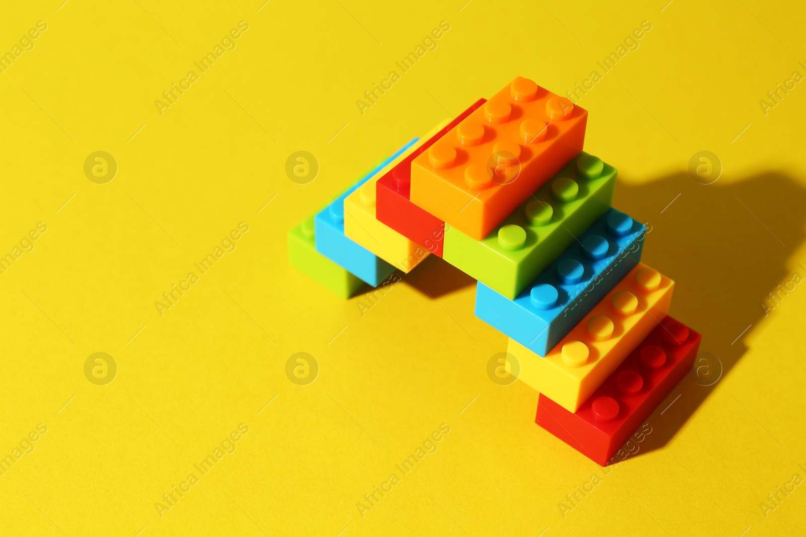 Photo of Construction toy. Figure made with building bricks on yellow background, space for text