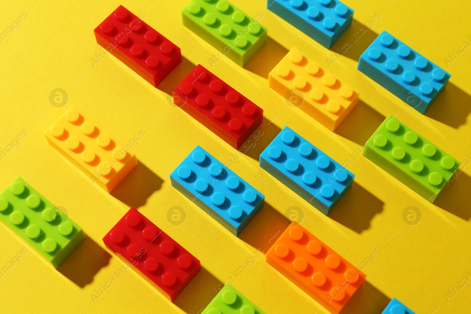 Photo of Construction toy. Colorful building bricks on yellow background, closeup