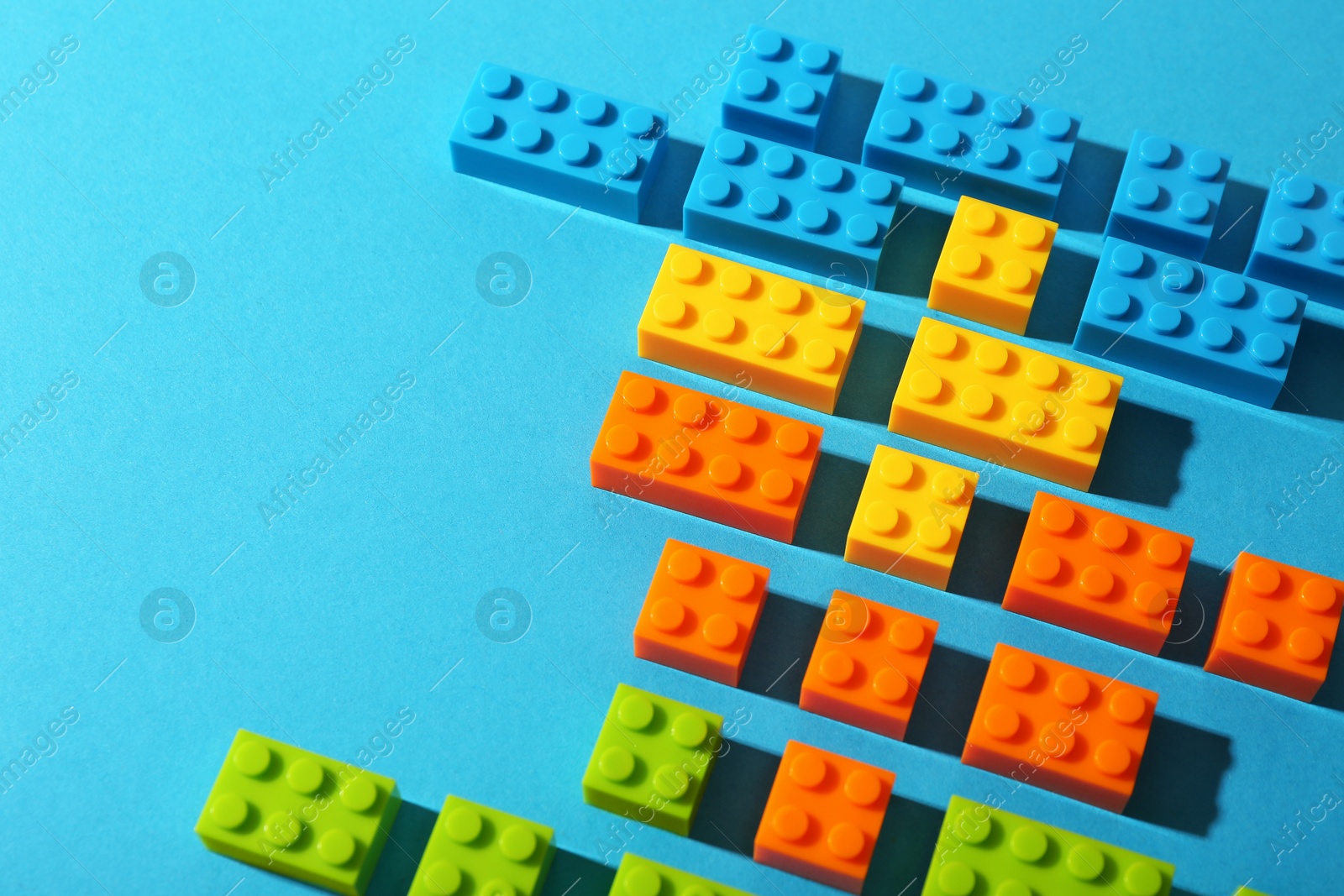 Photo of Construction toy. Colorful building bricks on light blue background, closeup