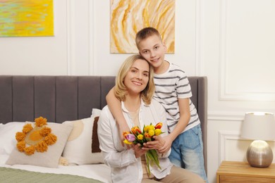 Photo of Happy Mother's Day. Son greeting his mom with flowers at home