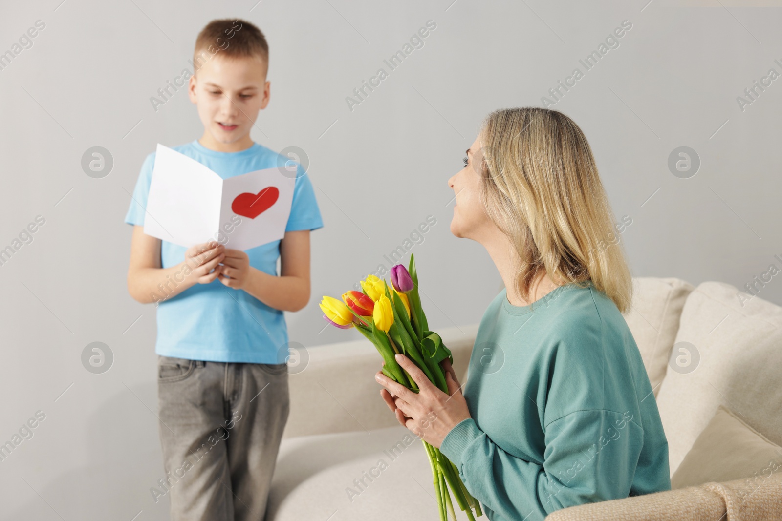 Photo of Happy Mother's Day. Son greeting his mom with flowers and card at home