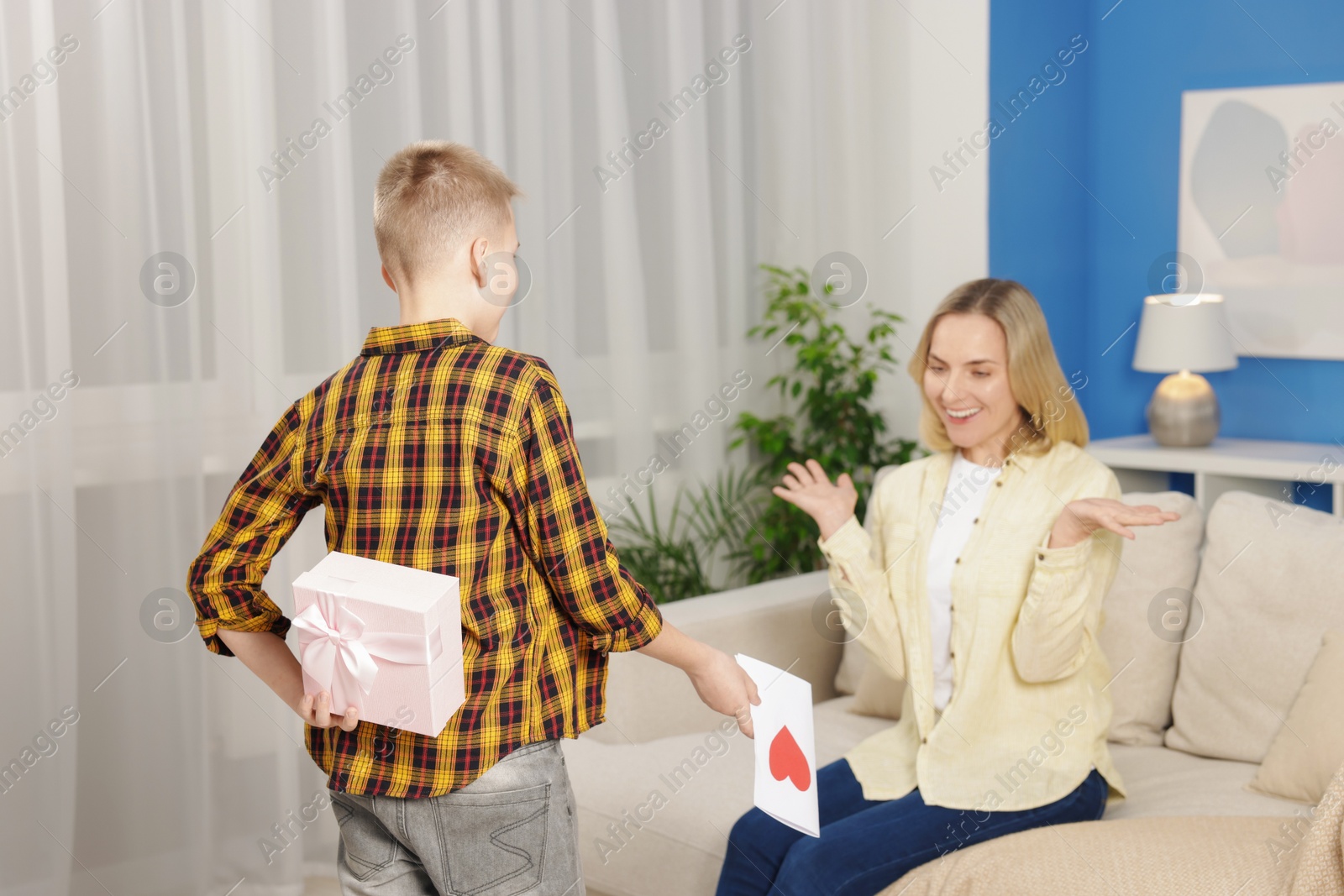 Photo of Happy Mother's Day. Son surprising his mom with gift and card at home, selective focus