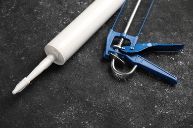 Glue gun and tube on black textured background, closeup