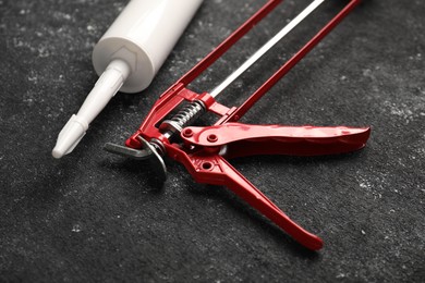 Glue gun and tube on black textured background, closeup