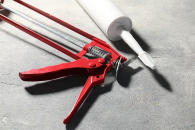 Glue gun and tube on grey background, closeup