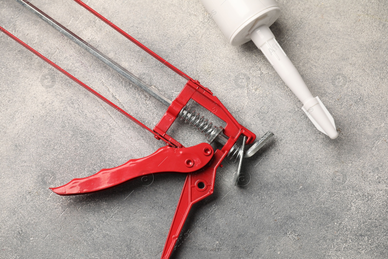 Photo of Glue gun and tube on grey background, closeup