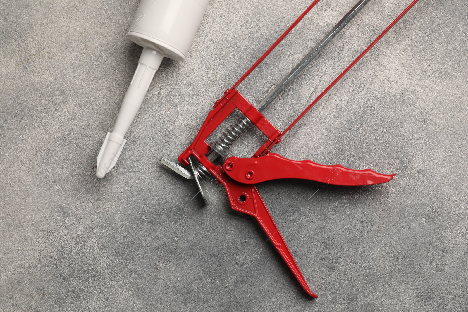 Photo of Glue gun and tube on grey background, top view