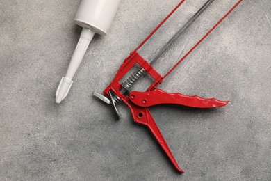 Glue gun and tube on grey background, top view