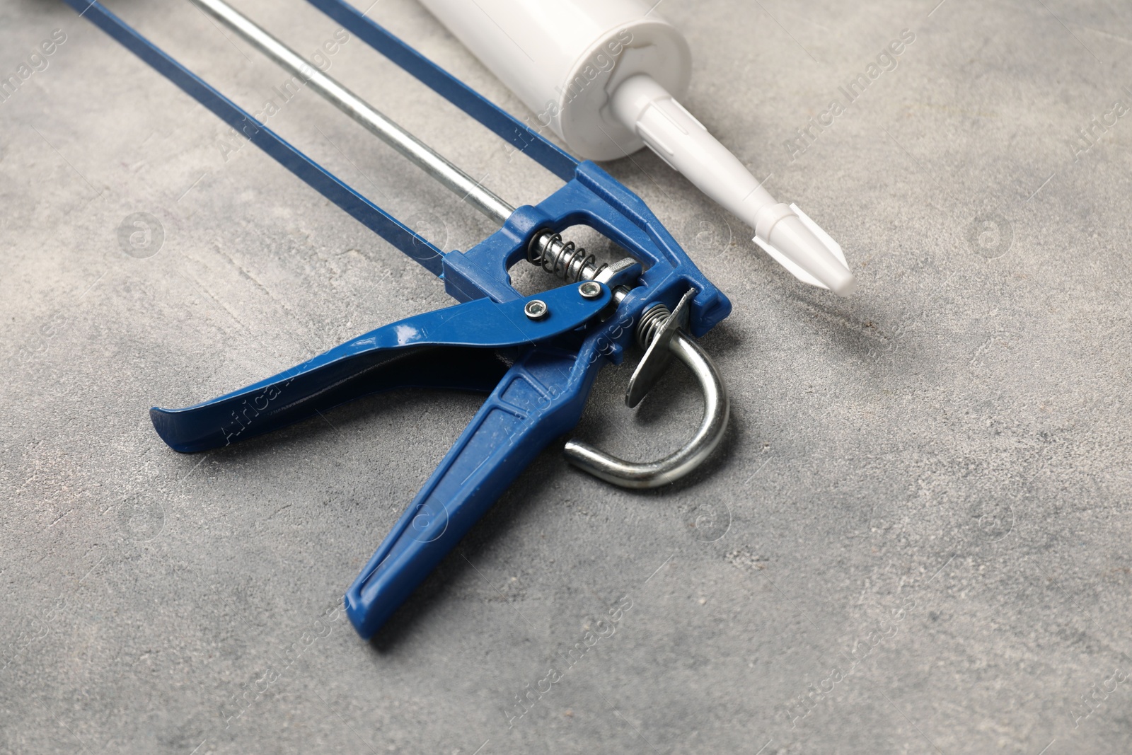 Photo of Glue gun and tube on grey background, closeup