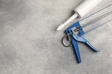 Glue gun and tube on grey background, top view. Space for text