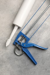 Glue gun and tube on grey background, top view